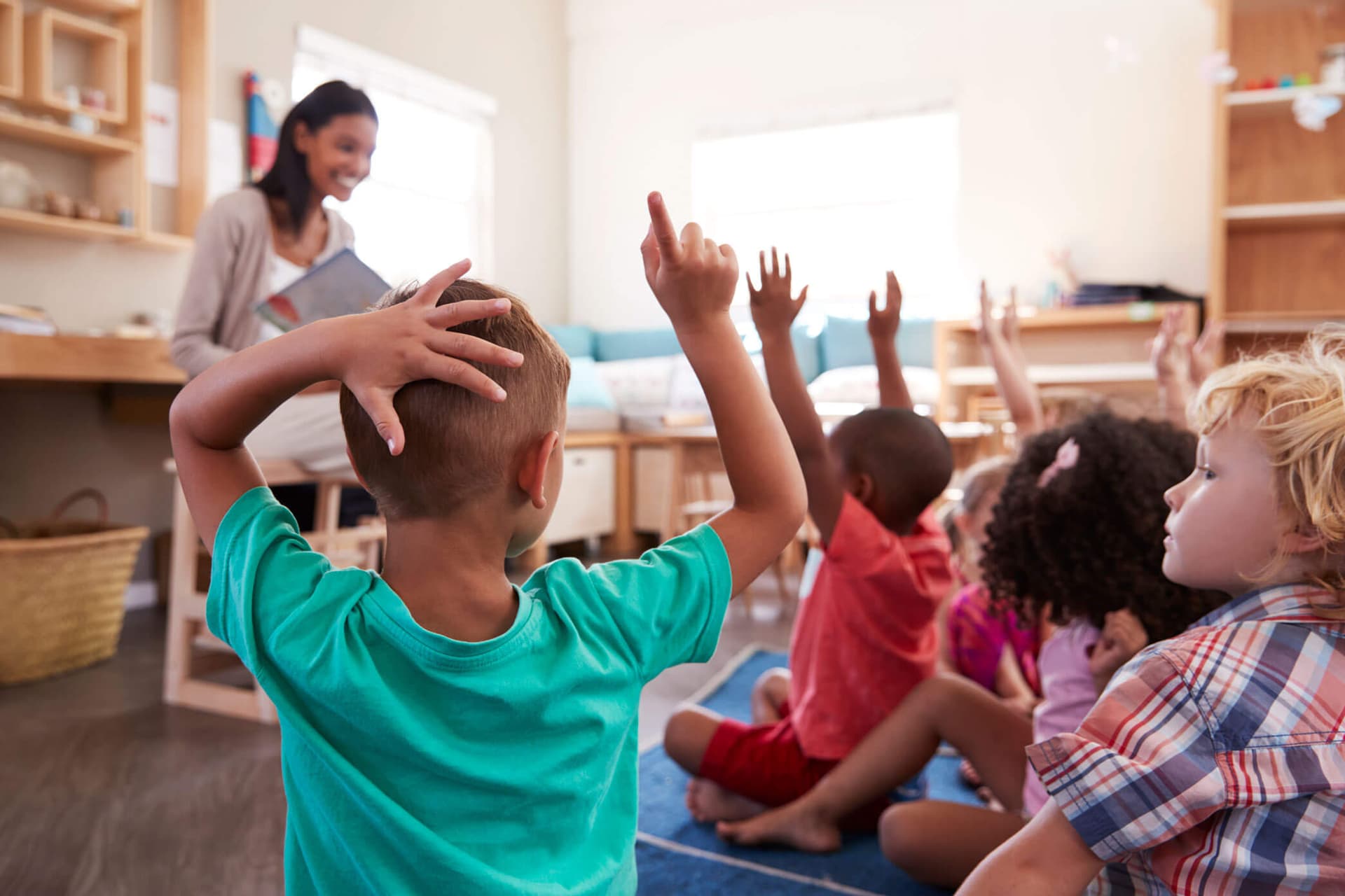Children raising their hands during circle time