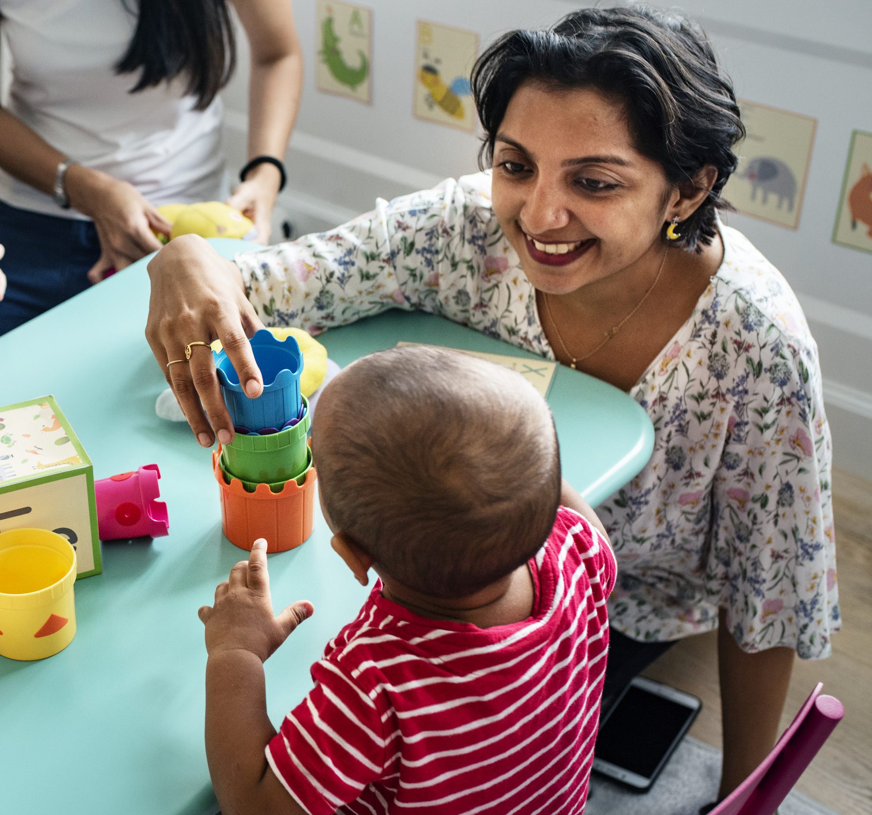 Young child building with blocks at a table with teacher.